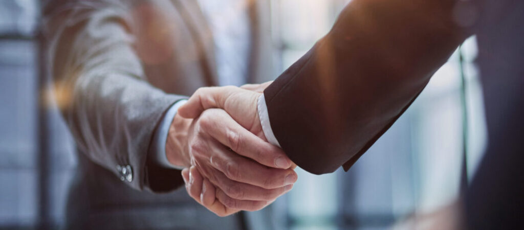 Two business men shaking hands in partnership between Optimal and institutional leaders.